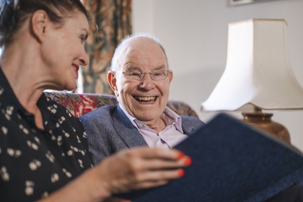 A man laughing with a woman who is showing him a book