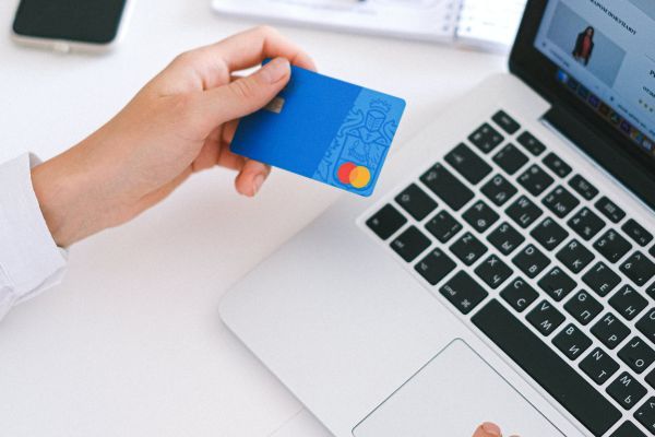 A man holding a credit card in front of a laptop