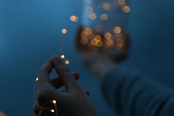 A person holding lit fairy lights