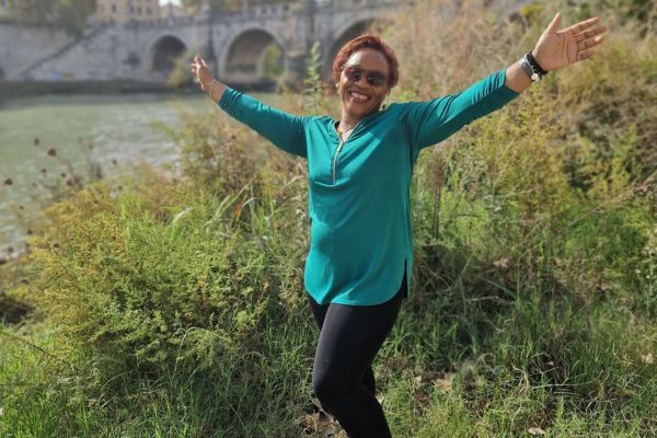 A lady standing next to a river with her hands outstretched