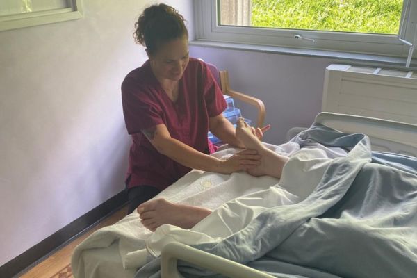 A reflexologist holding a patients foot