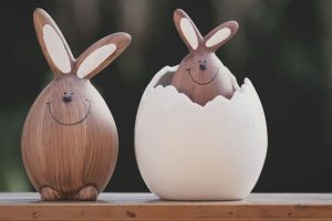 Two wooden Easter bunnies, with one inside an egg shell