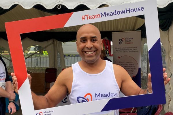 Amit holding up a Meadow House Hospice selfie frame.