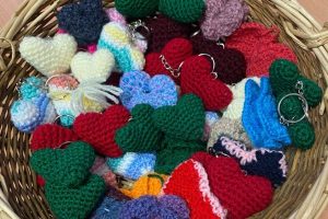 Different coloured knitted hearts in a basket.