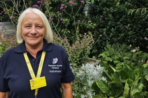 Jill standing in front of colourful flowers and plants.