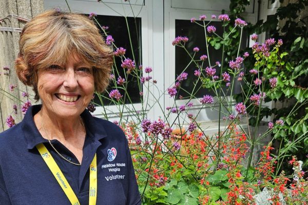 Maggie standing in front of colourful flowers and plants.