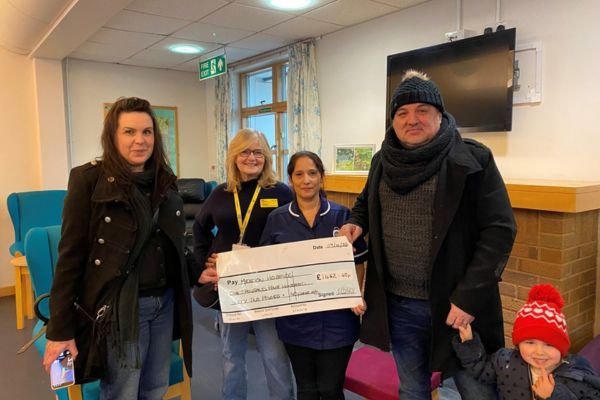 Lisa and Jason presenting a cheque to a member of staff.