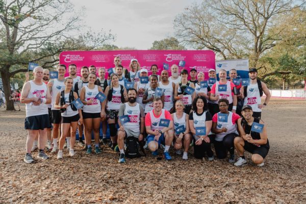 A group of runners wearing Meadow House Hospice branded vests and waving Meadow House Hospice flags.